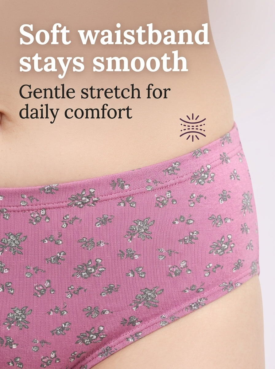 Close-up of a person wearing pink floral underwear with text reading 'Soft waistband stays smooth' and 'Gentle stretch for daily comfort' on a light gray background.